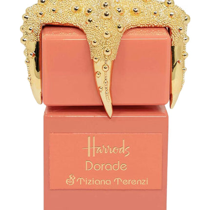 Coral-colored perfume bottle with gold decorative cap on a white background