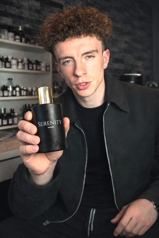 Person holding a black 'Serenity' perfume bottle in a store setting